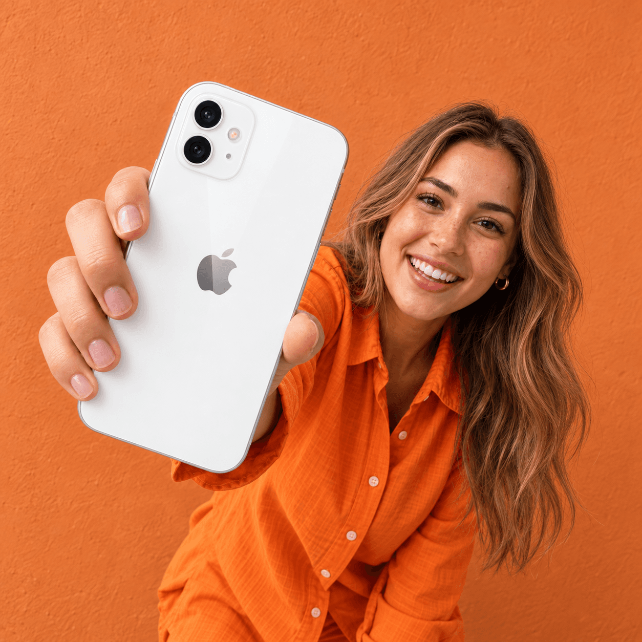 Chica sonriente enseñando a cámara la parte trasera de un iPhone blanco